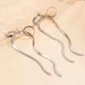 Detalle de pendientes de lazo plateado con elegantes borlas largas de cadena de serpiente - Pendientes de botón / Plateado