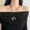 Close-up of sculptural silver C-shaped flower pendant with black cord on neck - Silver C-Shape Pendant