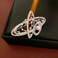 Macro shot of silver planet brooch with white pearl and sparkling zircons on black leather - Silver Planet Style