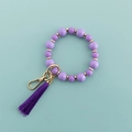 Gros plan d'un bracelet de téléphone en perles violettes avec anneau doré et gland - Violet