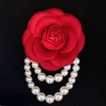 Elegant red camellia brooch with white pearl strands on a dark background - Red
