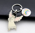 Detailed macro view of Schulkind rainbow charm and metal angel on golden keychain - Pink
