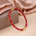 Detailansicht des rot-goldenen Armreifs im Bambus-Design auf Champagner-Seidenstoff - Rot