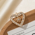 Macro detail of gold heart pendant with sparkling rhinestones and center starburst element - Hollow Design Style 3