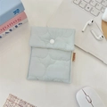 Dettaglio di una borsa igienica trapuntata azzurra con bottone a pressione su tavolo - Azzurro