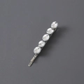 Detail of silver hair clip with five sparkling crystal rhinestones on a dark background - White Rhinestone / Silver Oval Style