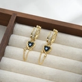 Dettaglio di orecchini a cuore dorati con pietre blu, zirconi e delicate nappe - Oro