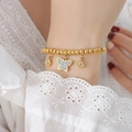 Bracciale di perline dorate con ciondoli a farfalla e cristallo sul polso di una donna - Oro