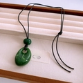 Close-up of green resin teardrop pendants on black wax cord in a velvet jewelry tray - Green (Teardrop)