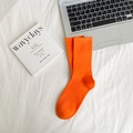 Solid bright orange combed cotton crew socks in ribbed knit on a cozy white fabric background - Orange Yellow