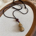 Detailed macro of wooden gourd pendant on wax cord with traditional Chinese weaving style - Brown Gourd