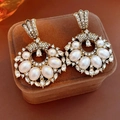 Macro detail of vintage gold fan-shaped earrings with pearls and crystals on velvet - Gold