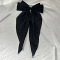 Elegant black bow hair clip with long chiffon ribbons on white textured background - Black