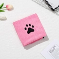 Detail of pink microfiber pet towel with black paw print embroidery on grid background - Pink