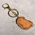 Detailed view of irregular brown agate slice keychain with golden metal plating edges - Irregular Size / Orange