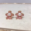 Macro shot of 18K gold flower earrings with pink enamel petals and a central white pearl - Pink