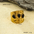 Macro shot of wide gold ring featuring hammered texture and three black stones in sand - Black