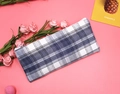 Dettaglio astuccio in tela a scacchi blu con cerniera su sfondo rosa con rose decorative - Quadri blu e bianchi