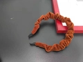Detailed view of a brown pleated velvet headband with black tips on a matte background - Tan