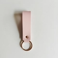 Porte-clés minimaliste en similicuir rose avec anneau doré sur un fond blanc épuré - Rose