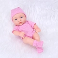Reborn baby doll in pink polka dot romper and matching hat lying on white fur - Plum Pink Polka Dot