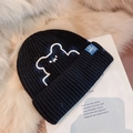 Black knit beanie with white bear embroidery and blue label on a soft plush background - Bear Embroidered Style / Black