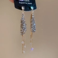 Nahaufnahme eleganter goldener Quastenohrringe mit grauen Kristallen und funkelnden Ketten - Grau