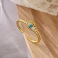 Close-up of golden Evil Eye open ring with blue enamel on a rustic wood surface - 13851-Gold Evil Eye Enamel