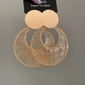 Macro detail of gold geometric hollow round earrings with textured woven metal design - Gold