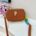 Close-up of brown rectangular crossbody bag featuring a gold P logo and colorful chain strap - Coffee