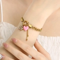 Dettaglio del braccialetto dorato con ciondoli a cuore rosa e fiori indossato sul polso - Stile Catena a Maglia Fiore Zirconia Cuore Rosa (KB204438-SXSJ)