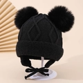 Detailansicht der schwarzen Kinder-Strickmütze mit Rautenmuster, Bommeln und Bindebändern - 1-3 Jahre / Schwarz