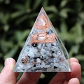 Hand holding Orgone pyramid with white stone and copper coil on green background - Moonstone Crystal Column / Small