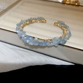 Detail view of handmade open bangle with light blue crystals and white pearls on gold wire - Pearl Crushed Gold Aquamarine Open Cuff