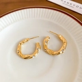 Detalle de pendientes de aro en C dorados con textura martillada y circonitas cúbicas - Dorado (Pin de Plata S925)