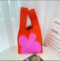 Chic knit tote bag featuring bold orange color and large pink floral pattern - Orange Clover