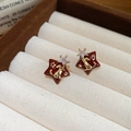 Macro shot of 18k gold plated star stud earrings with burgundy enamel and cat motif - Cat Star Style / Red