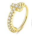Nahaufnahme eines goldenen Kreuzrings mit weißen Kristallen auf weißem Grund - Pavé Kreuz Design / Gold
