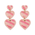 Close-up of dangling heart earrings with pink striped beads and gold-tone finish - Pearl Striped Heart