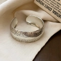 Detailed macro view of vintage silver textured cuff bracelet with engraved floral patterns - Silver