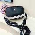 Detail of black pebbled leather crossbody bag with white wavy trim and gold T-logo - Black (Apricot Strap)