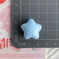 Macro shot of 2.5cm light blue star resin accessory on a metric measurement grid mat - Big Star / Blue