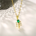 Gold leaf necklace with emerald green teardrop gemstone and crystal accents on a light surface - Gold with Green Zirconia