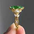Close-up of golden leaf ring featuring green marquise stone and white cubic zirconia - US 7 / Green
