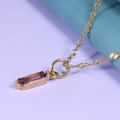 Primer plano de un collar dorado ondulado con colgante rectangular de circón morado - Granate Púrpura Marrón (Enero) - Dorado