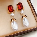 Dettaglio ravvicinato di orecchini vintage con perle e gemma rossa in una scatola regalo - Oro-Rosso-Bianco