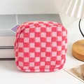 Close-up of pink checkered knit pouch with golden zipper on a cozy desktop setting - Red