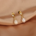 Macro detail of star-shaped gold earrings with zircons and drop-shaped freshwater pearls - ER1466-A Star Zirconia Waterdrop Pearl