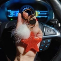 Star keychain with red rhinestones and white fur ball held in car interior - Orange Red