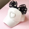 Dettaglio di cappello bianco da bambina con fiocco in pizzo nero e accenti di perle - Stile per Tutte le Stagioni / Bianco